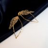 Les boucles d'oreilles Folÿs 3 sont des bijoux uniques brodés à la main par la marque Marie Archambaud. Elles reposent délicatement sur un tissu bleu marine, mettant en valeur l'éclat doré du métal. Elles sont composées de deux feuilles légères évoquant une nature délicate.