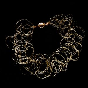 Bracelet Lumi sur fond noir, en fil de cuivre vernis à l'or, fin et élégant.