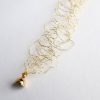 Détail du bracelet Lumi en or jaune et son fermoir aimanté. Maille métallique en cuivre vernis à l'or créée par Marie Archambaud, marque de bijoux brodés uniques.