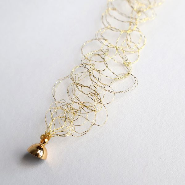 Détail du bracelet Lumi en or jaune et son fermoir aimanté. Maille métallique en cuivre vernis à l'or créée par Marie Archambaud, marque de bijoux brodés uniques.